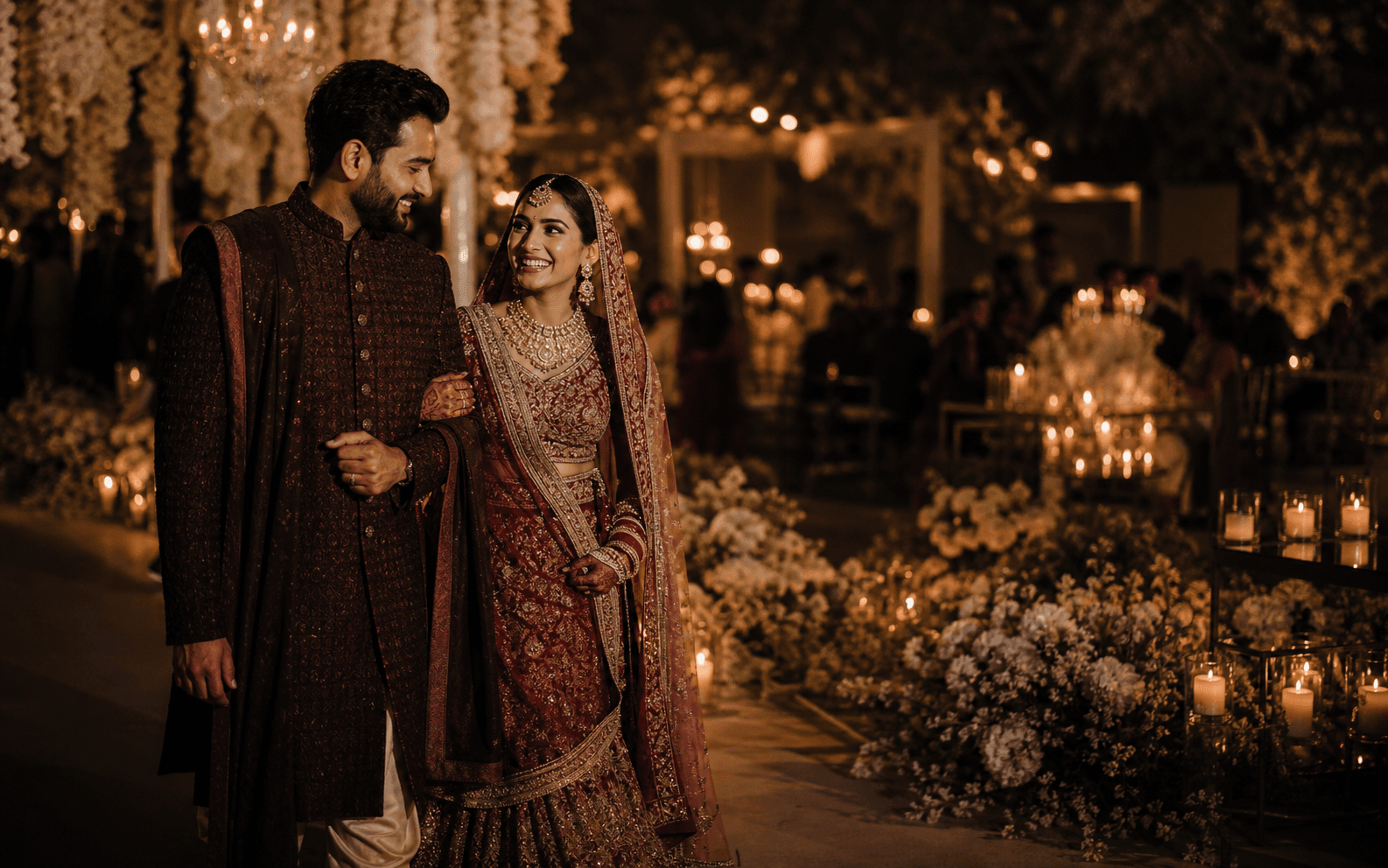 Indian newlywed couple walking through an elegant candlelit wedding reception